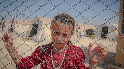 Refugee girl behind fence.